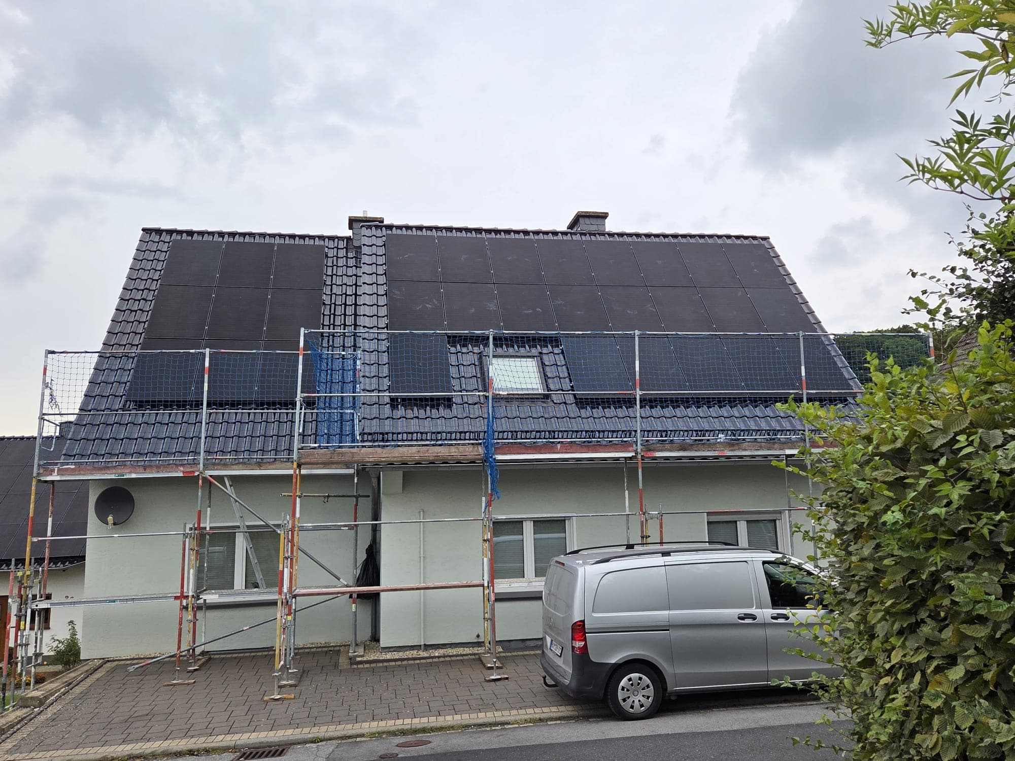 Einfamilienhaus mit Full-Black-Photovoltaikmodulen auf beiden Dachflächen während der Montage