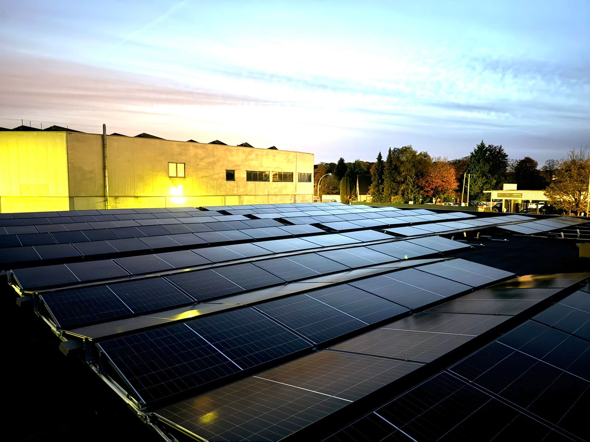 Gewerbliche Photovoltaik-Flachdachanlage auf einer Industriehalle in der Abenddämmerung