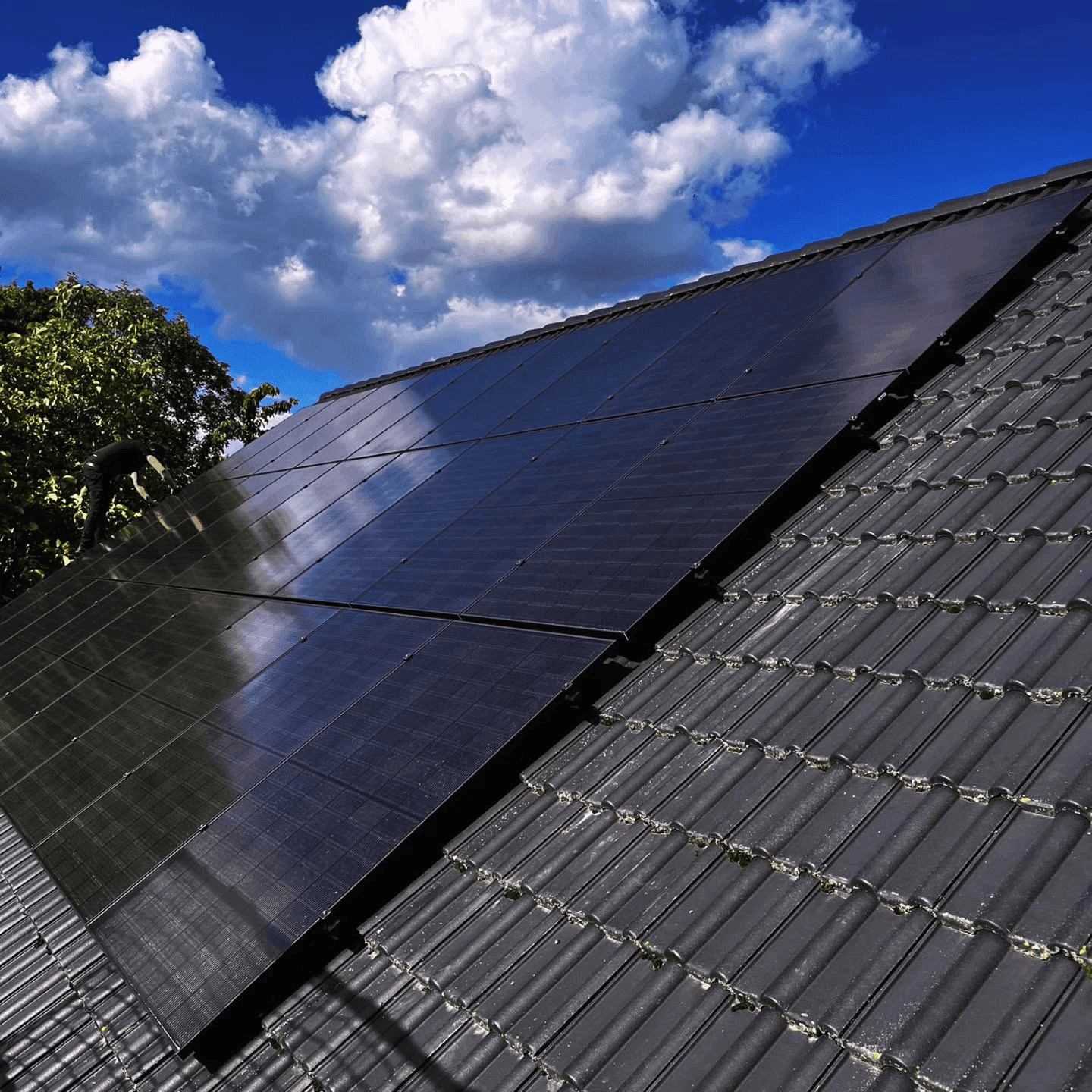 Techniker bei der Montage von Full-Black-Solarmodulen auf einem Ziegeldach